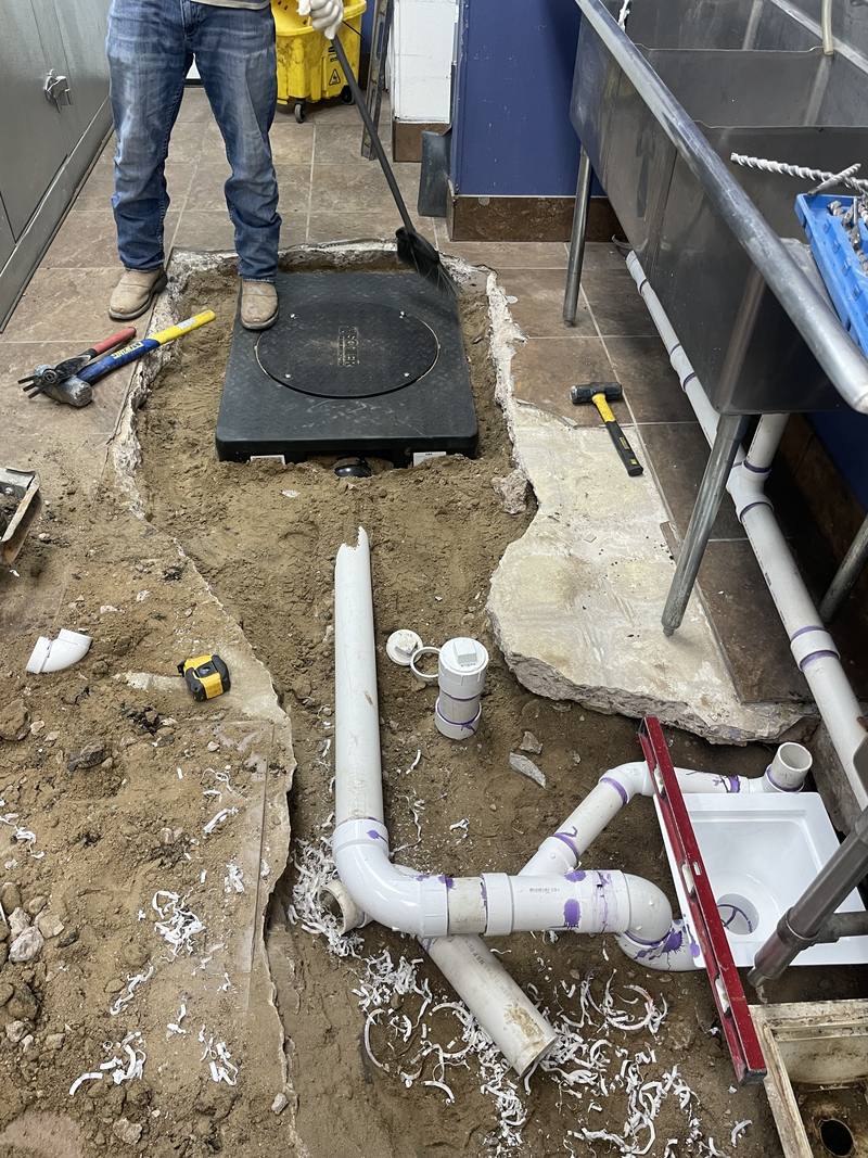 New black poly grease interceptor set in the kitchen floor with new white PVC plumbing